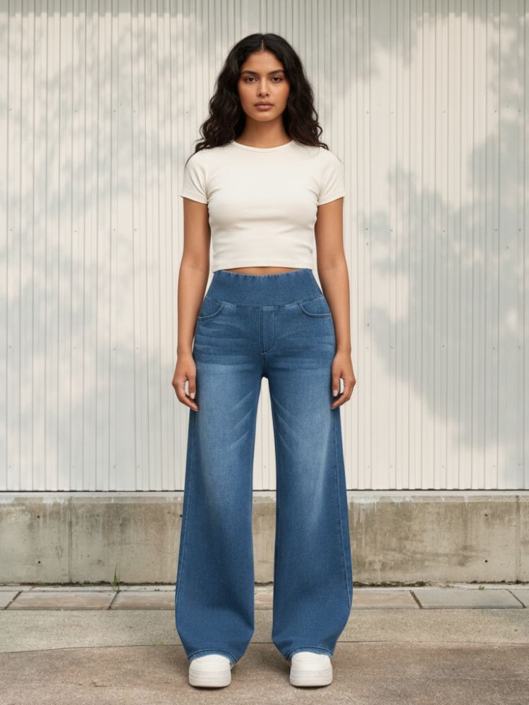 Femme portant un t-shirt blanc avec un jean ample bleu délavé avec la taille élastique, sur fond clair