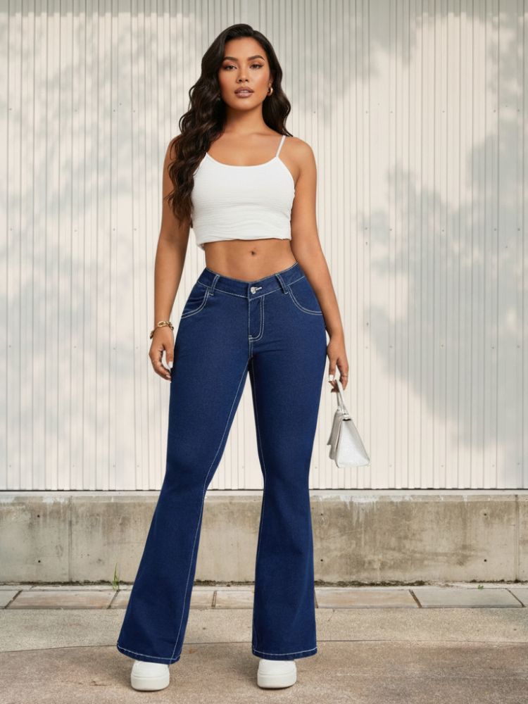 Femme brune avec un top blanc et un jean bootcut bleu brut, sur fond clair