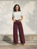 Femme brune portant un t-shirt blanc et un jean large bordeaux élégant sur fond clair