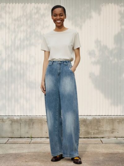 Femme noire portant un t-shirt blanc et un jean large délavé au style vintage sur fond clair