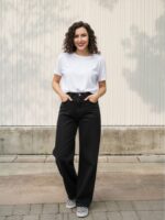 Femme brune portant un jean noir taille haute et large sur fond clair