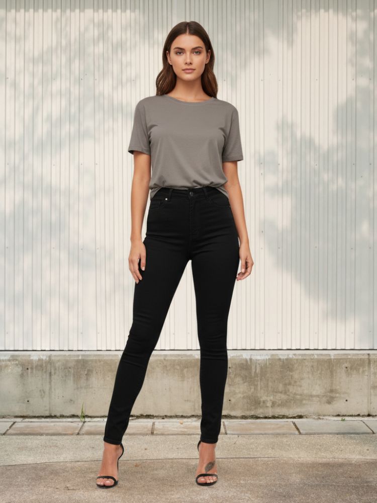 Femme portant un t-shirt gris et un jean skinny taille haute de couleur noir, sur fond clair