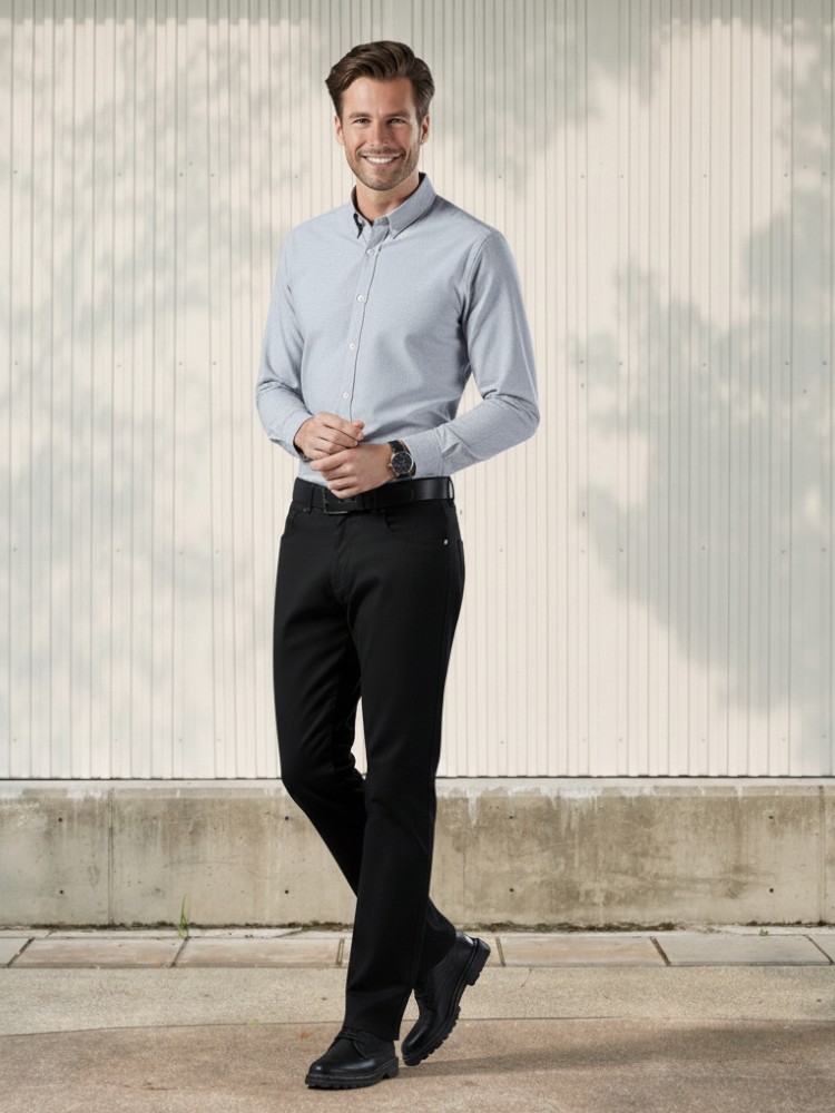 Homme caucasien châtain avec une chemise manche longue grise et un jean noir profond en denim souple a la coupe regular pour un style classique et habillé dans un endroit lumineux.