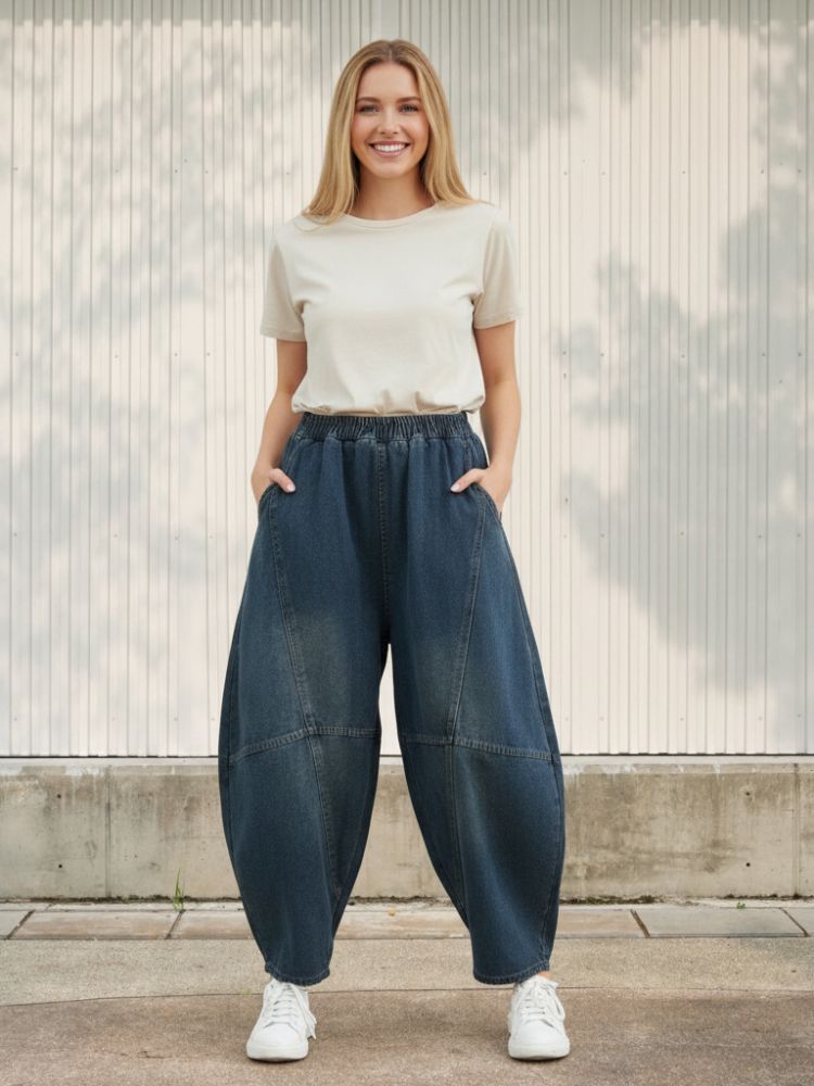 Femme portant un t-shirt beige avec un jean ballon bleu foncé délavé, sur fond clair