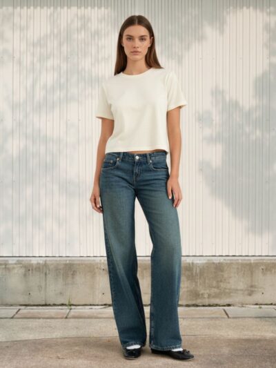 Femme portant un t-shirt blanc et un jean droit taille basse à coupe ample, sur fond clair