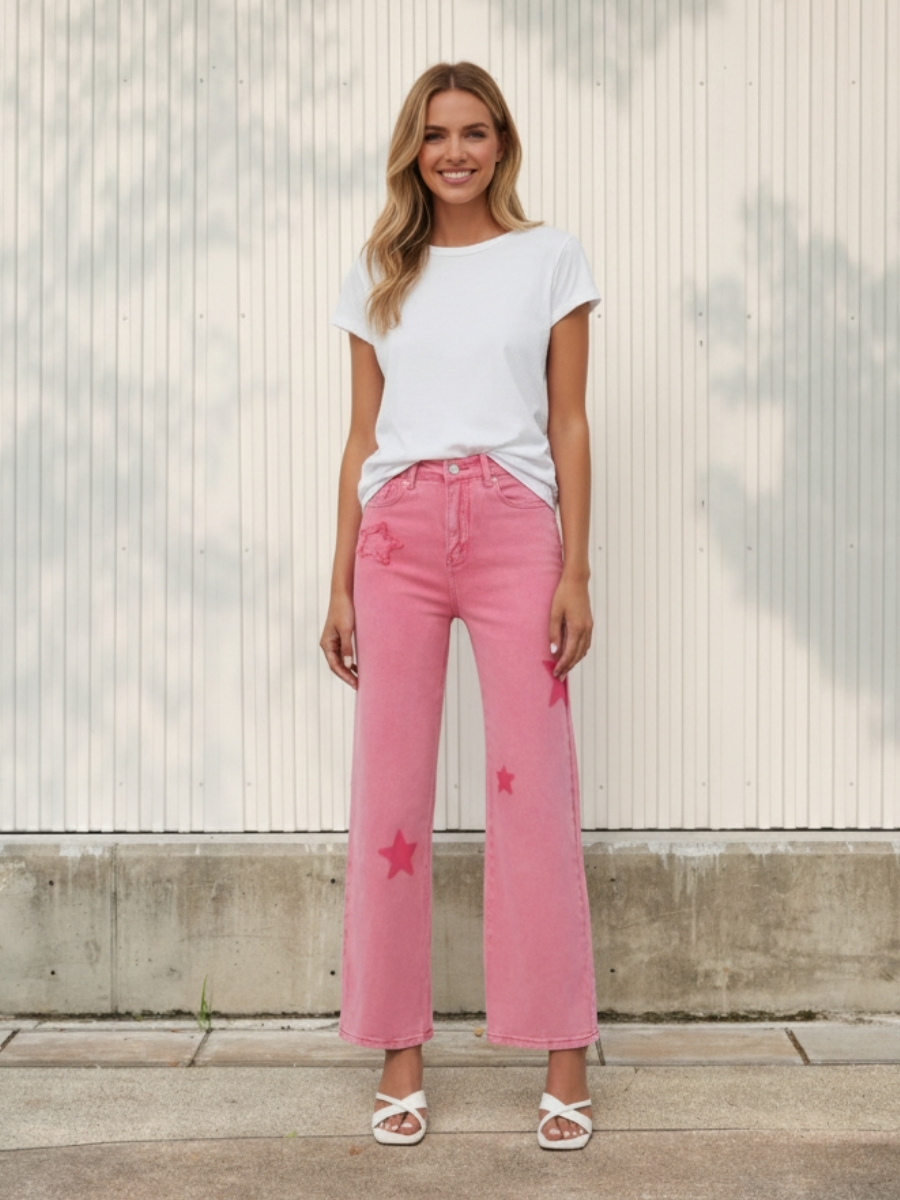 Femme portant un t-shirt blanc et un jean rose taille haute à motif étoiles, sur fond clair