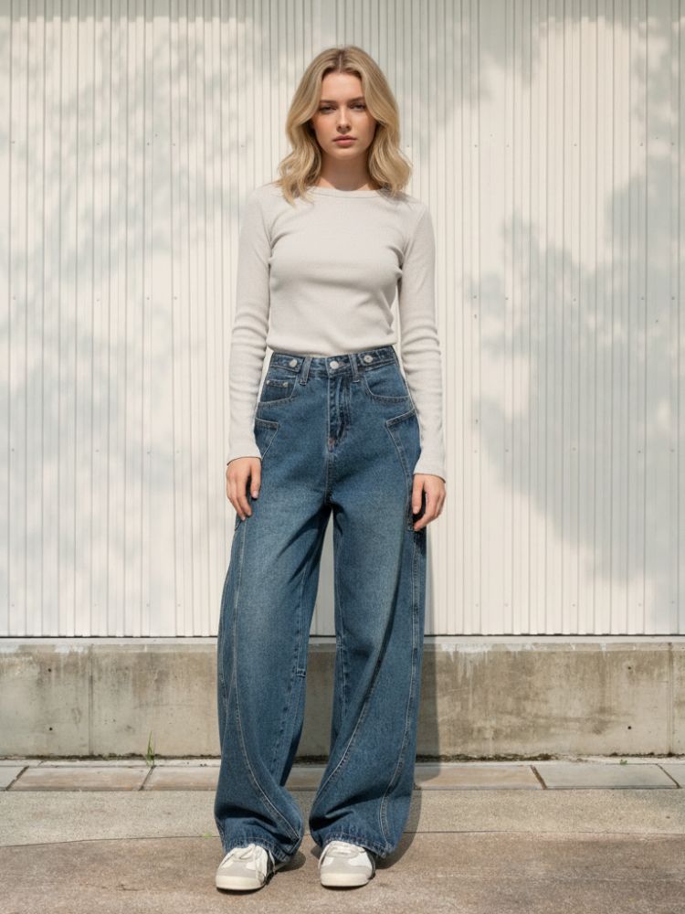 Femme portant un haut blanc à manches longues avec un jean large au style vintage, sur fond clair