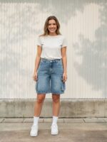 Femme portant un short en jean bleu vintage coupe cargo avec un t-shirt blanc, sur fond clair