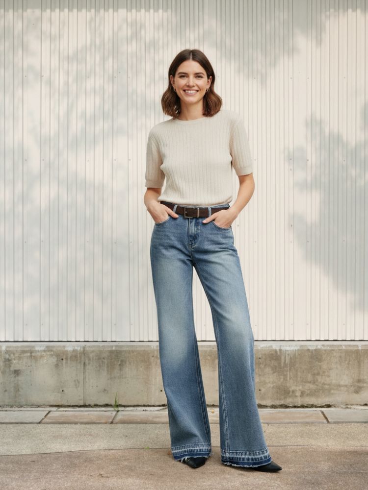 Femme avec un t-shirt beige et un jean flare bleu clair délavé, sur fond clair