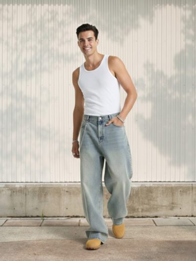 Jeune homme en débardeur blanc habillé d'un jean baggy teinte vintage relief profond sur fond clair.