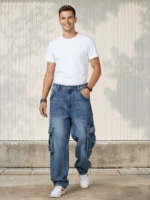 Jeune homme portant un jean cargo bleu aux poches amples dans un lieu ensoleillé.