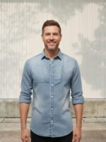 Homme portant une chemise en jean bleu délavé à coupe slim, sur fond clair