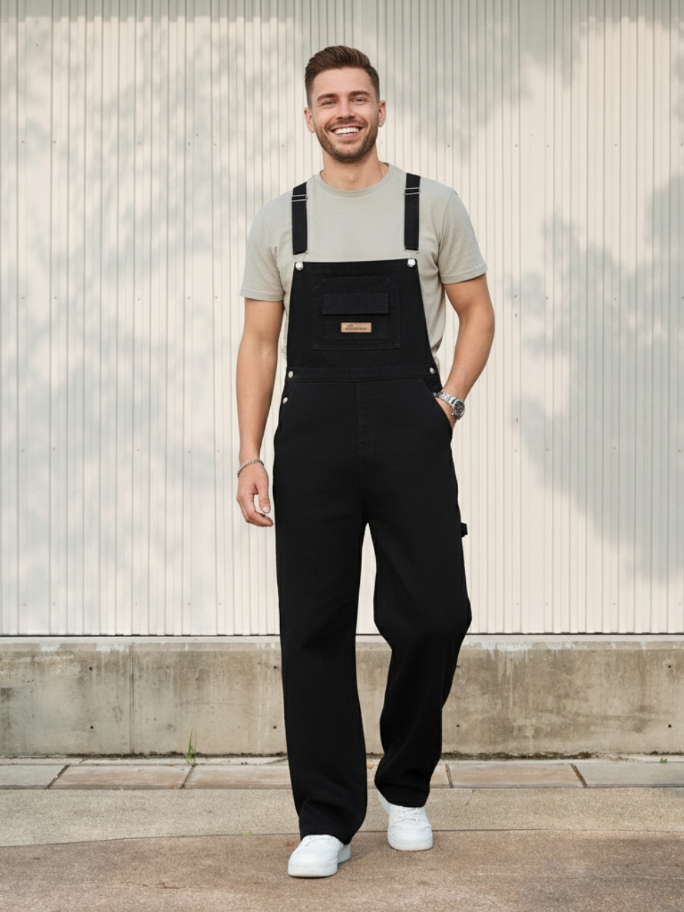 Homme portant un t-shirt beige avec une salopette en jean noir, sur fond clair