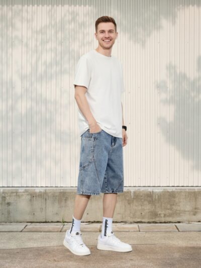 Homme portant un t-shirt blanc avec un short en jean à coutures contrastées, sur fond clair