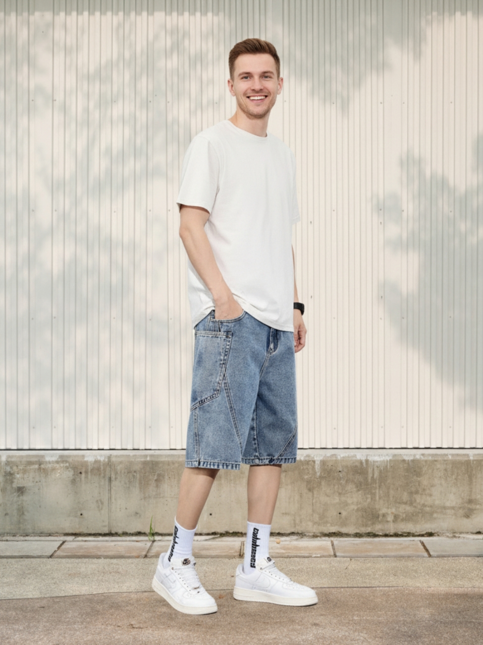 Homme portant un t-shirt blanc avec un short en jean à coutures contrastées, sur fond clair