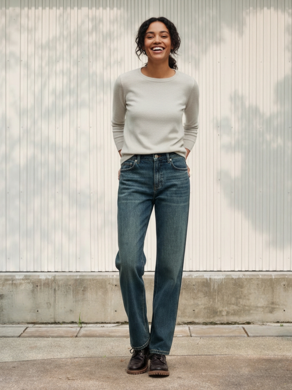Femme portant un haut gris avec un jean mom taille haute, sur fond beige