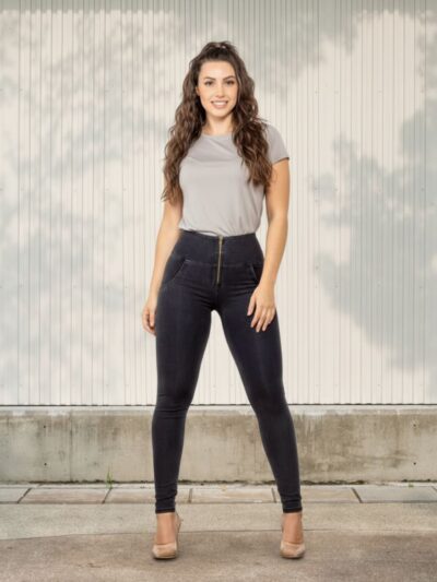 Femme portant un t-shirt beige avec un jean push up noir, sur fond beige