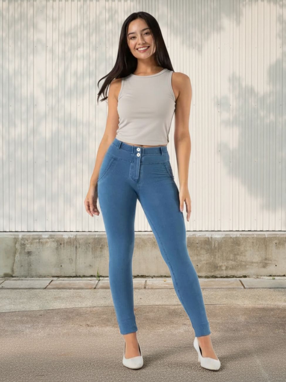 Femme portant un top beige avec un jean push up bleu, sur fond clair