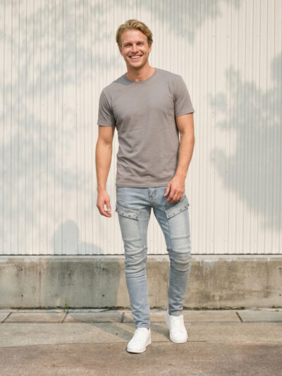 Homme portant un t-shirt taupe avec un jean skinny bleu clair à poches cargo, sur fond clair