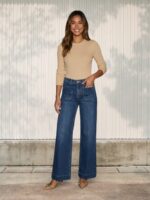 Jeune femme caucasienne dans un lieu clair, portant un jean taille haute wide leg bleu foncé.