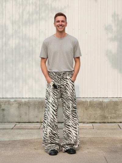 Homme portant un t-shirt gris avec un jean large imprimé zèbre, sur fond beige