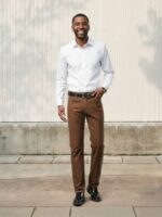 Homme portant une chemise blanche avec un jean marron coupe regular, sur fond beige