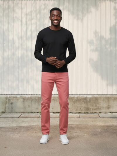 Homme portant un pull noir avec un jean slim rose, sur fond beige