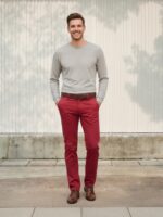 Homme portant un pull beige avec un jean slim fit rouge, sur fond beige