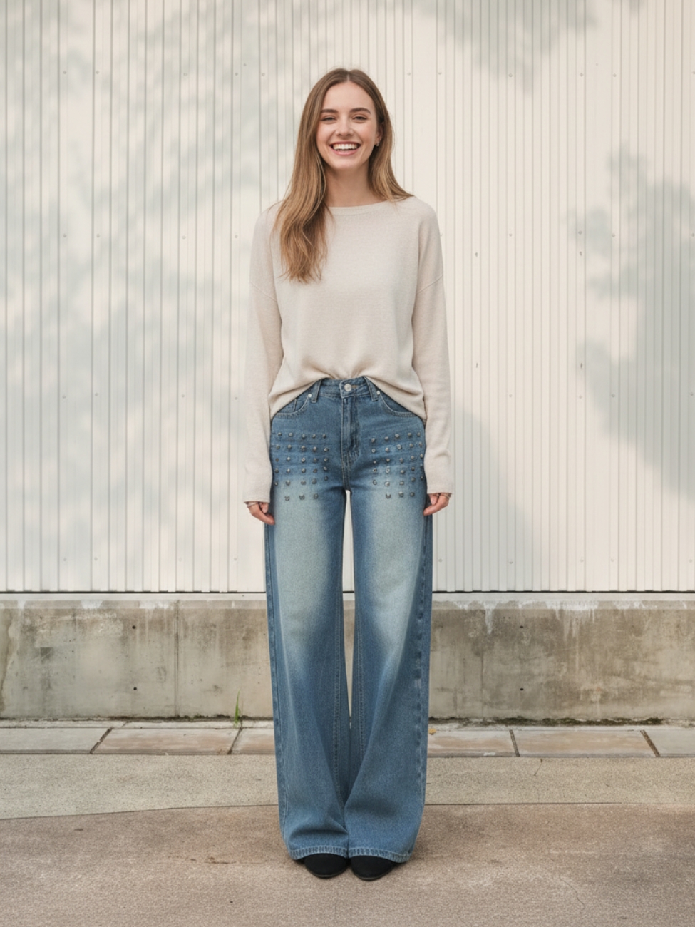 Femme portant un pull beige avec un jean vintage délavé, sur fond beige