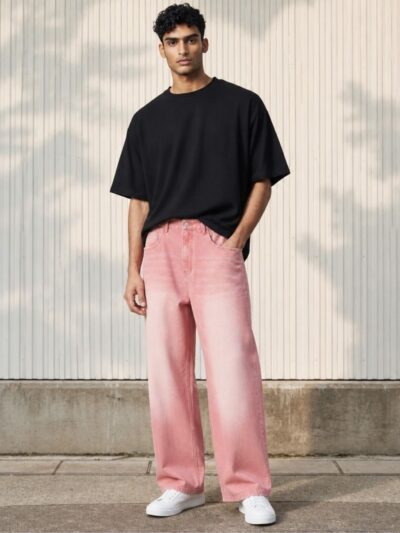Homme portant un tshirt noir avec un jean rose à coupe loose, sur fond beige