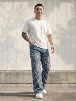 Jean moto homme bleu destroyed bandages vintage large porté par un homme, coupe droite ample, denim bleu délavé, déchirures visibles, bandages décoratifs, style streetwear rétro affirmé.