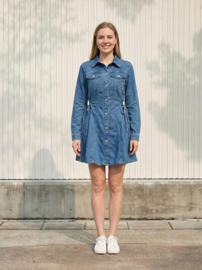 Femme portant une robe courte en jean à manches longues, sur fond beige