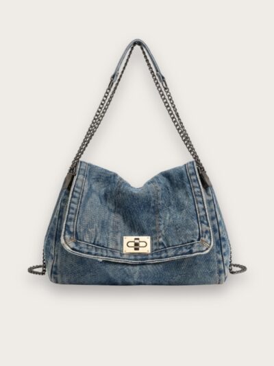 Sac à main en jean bleu porté épaule avec une chaînette, sur fond gris