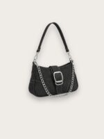 Sac à main en jean noir porté épaule format baguette avec une chaîne argentée, sur fond gris