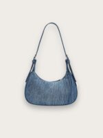 Sac à main en jean bleu porté épaule format croissant, sur fond gris