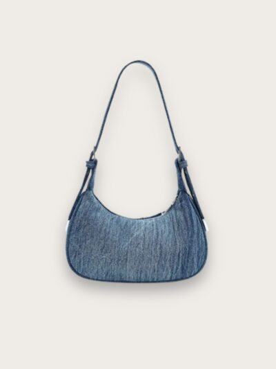 Sac à main en jean bleu porté épaule format croissant, sur fond gris